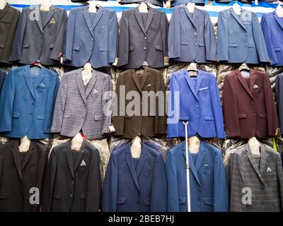 Rows of hanging new men's suits on the market. Stock Photo
