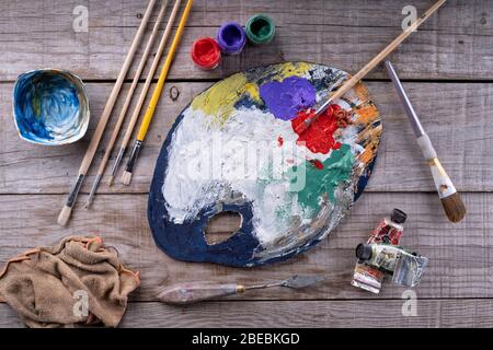 Paintbrushes, artist palette, oil paints on desk in painter studio. Close up. Stock Photo