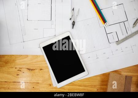 Construction blueprints with tools and tablet, top view. Tablet with architectural blueprints and measuring tools on wooden table. Stock Photo