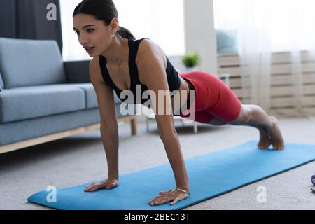 Woman doing a fitness at home in a living room. Training to become the best.