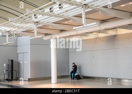 A man sits in Toronto's Pearson International airport, March 16, 2020. Amid security measures directed at slowing the spread of the COVID-19 virus, Canada's Prime Minister Justin Trudeau restricted travel to Canada, from many international countries. Pearson will be one of the designated airports in Canada that will be allowed to accept limited international flights. Stock Photo