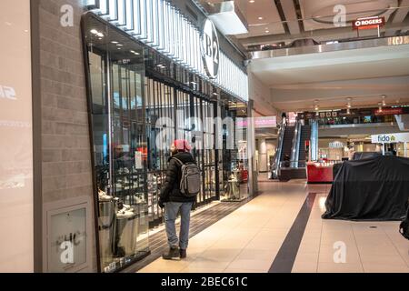 A man surveys closed stores in the Eaton Center mall in downtown Toronto, Canada, March 17, 2020. Amid security measures directed at slowing the spread of the COVID-19 virus, the Province of Ontario declared a state of emergency March 17, 2020. The new regulations will largely restrict people going to restaurants and will close bars, gyms, churches, among others. Stock Photo
