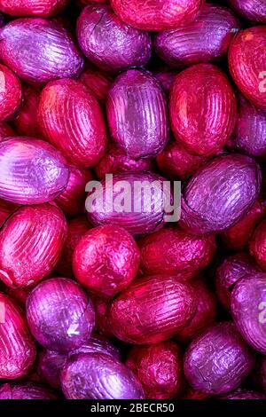 A top down close up portrait of a bunch of colorful chocolate easter eggs wrapped in tin foil lying on top of each other. Ready to be eaten. They are Stock Photo