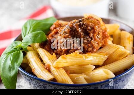 Bowl of homemade ziti pasta on a lace place mat with a sprig of basil Stock Photo