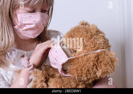 little girl with homemade covid 19 protection playing with her teddy bear Stock Photo