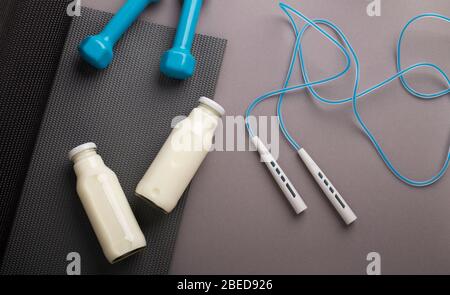 Jump rope, dumbbells, mat, detox water on gray background Stock Photo