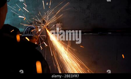 A worker using a grinder cut metal. Processing a metal product using a manual grinder. Stock Photo