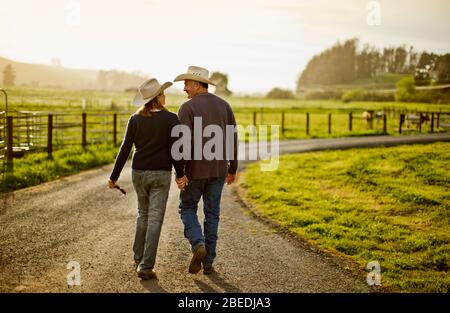 Happy mid adult couple smiling at one another while walking on a farm. Stock Photo