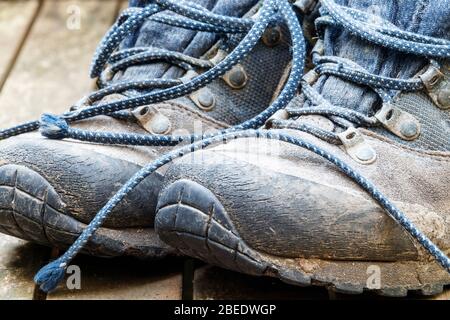 A pair of worn-out muddy lace-up hiking boots Stock Photo