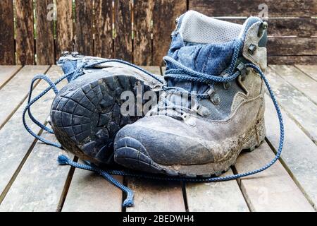 A pair of worn-out muddy lace-up hiking boots Stock Photo