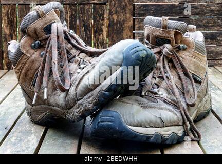 A pair of worn-out, split and muddy lace-up hiking boots Stock Photo