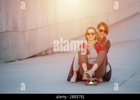 Two young female friends having fun with skateboard together Stock Photo