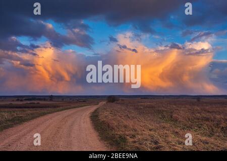 Path to cumulonimbus red storm clouds at sunset, beautiful landscape Stock Photo