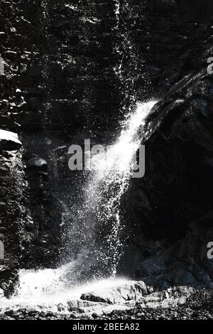 view of a waterfall with drops and splashes falling on a black rock Stock Photo