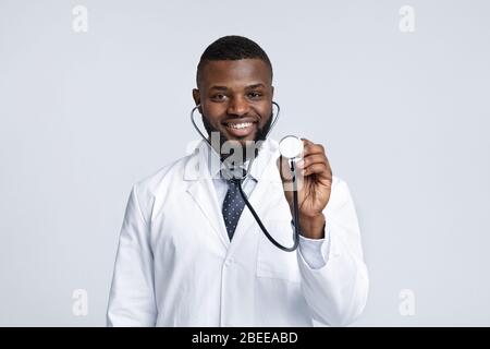 Portrait of cheerful african therapist checking on patient lungs Stock Photo