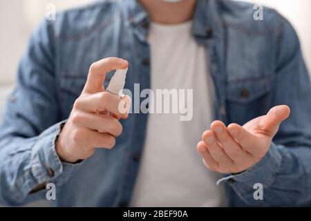 Man disinfecting hands at home, close up Stock Photo