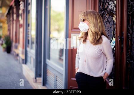 Portrait shot of middle aged woman wearing face mask while standing on the street during the coronavirus outbreak. Stock Photo