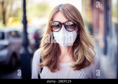 Close-up shot of middle aged woman walking on the street and wearing respirator mask for health protection while rapidly spreading coronavirus outbrea Stock Photo