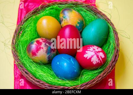 Green grass nest in a basket with colored chicken Easter eggs, multicolored painted eggs, Easter tradition, celebration concept Stock Photo