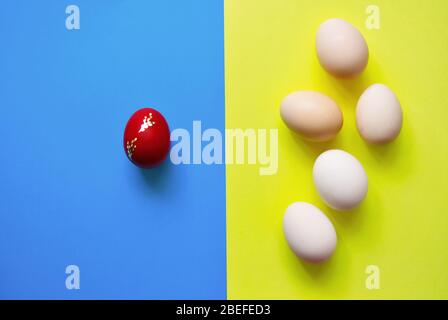 White Easter eggs on blue and yellow background with one red egg . Stock Photo