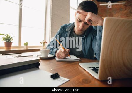Creative workplace - organized work space as you like for inspiration. Man working in office in comfortable attire, relaxed position and messy table. Choose atmosphere you want - ideal clear or chaos. Stock Photo