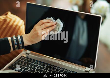 Closeup on woman wiping laptop display with cleaning cloth in the living room in sunny day. Stock Photo