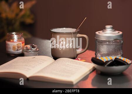 Coffee Cup with open Book and Cookies on Desk Stock Photo