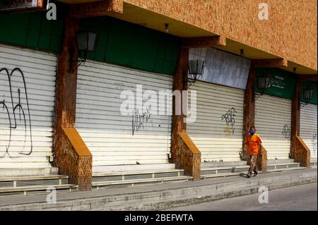 Guacara, Carabobo, Venezuela. 13th Apr, 2020. April 13, 2020. A man walks in front of some closed shops in the streets of the central town of Guacara, Carabobo state. Photo: Juan Carlos Hernandez Credit: Juan Carlos Hernandez/ZUMA Wire/Alamy Live News Stock Photo