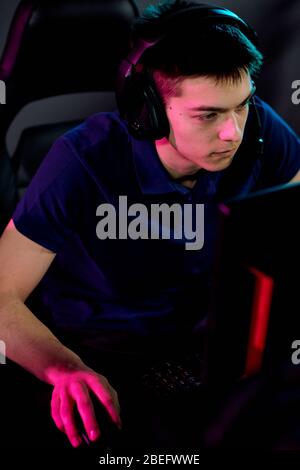 Addicted young male gamer in headset with microphone using computer mouse while playing network video game Stock Photo