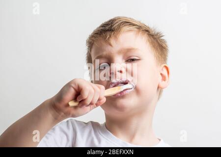 cute boy posing with bamboo toothbrush in his mouth, child brushes his teeth Stock Photo