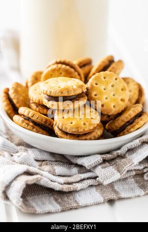 Mini cream sandwich cookies in bowl on white table. Stock Photo
