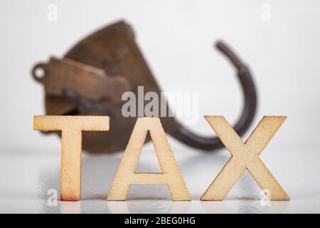 TAX inscription made of wooden letters. Taxes and an old padlock. Light background. Stock Photo