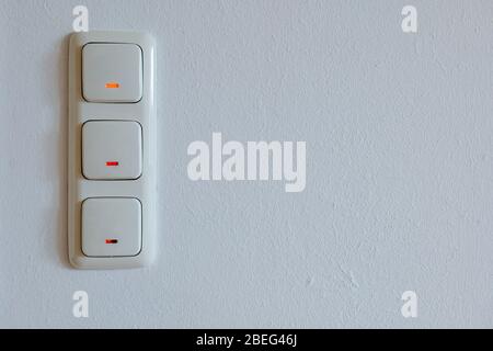 Triple European light switches on white plaster interior wall. Stock Photo