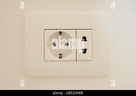 A block of white outlets consisting of one EU standard outlet with grounding and one US standard outlet. Stock Photo