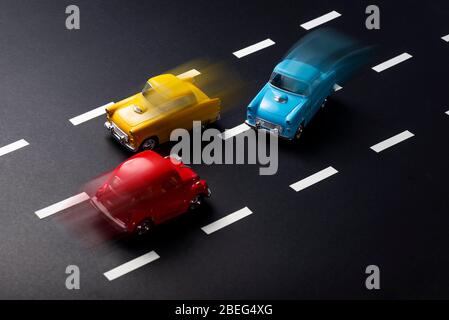 Incorrect overtaking with motion blur by toy model cars on a road with stripes. Stock Photo