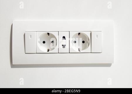 Block of white outlets, consisting of two EU standard outlets with grounding and one US standard outlet and two switches with LED backlight. Stock Photo