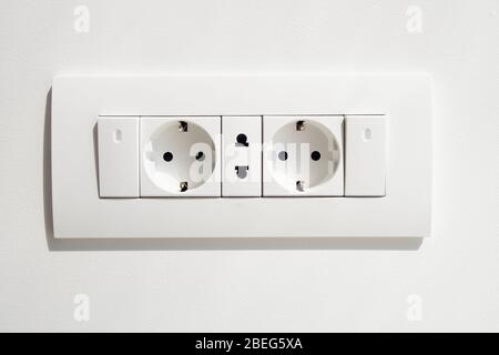 Block of white outlets, consisting of two EU standard outlets with grounding and one US standard outlet and two switches with LED backlight. Stock Photo
