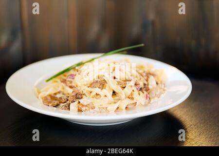 Plate of tagliatelli carbonara italian food in a rustic restaurant setting