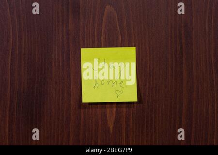 Stay home virus quarantine concept with post-it adhesive note. Written message on a yellow sticky paper against wooden background. Stock Photo