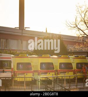 Multiple yellow and white ambulance vans parked in a line in public hospital, Split, Croatia. Bright morning sunrise sky, emergency worker walking nea Stock Photo