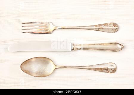 Vintage knife, fork and spoon on white wooden background. Stock Photo