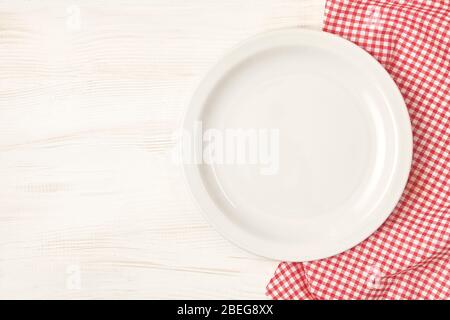 Empty plate with red napkin over white wooden table background. Stock Photo