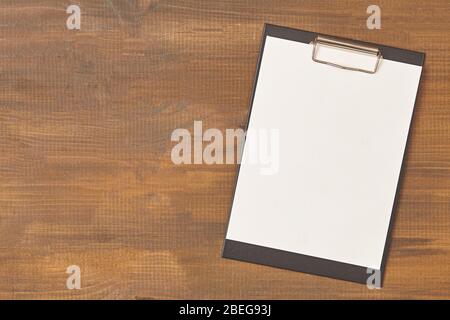 Clipboard with a blank sheet of paper on wooden table with copy space Stock Photo