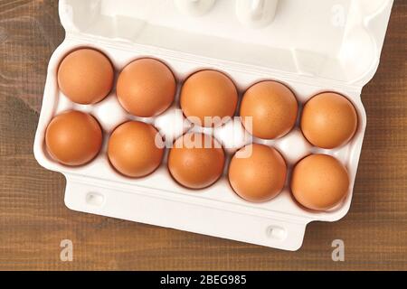 Raw chicken eggs in egg box on wooden table. Top view Stock Photo