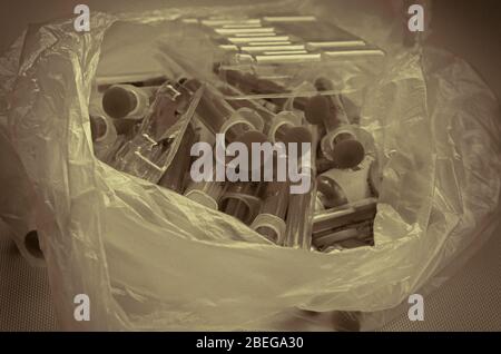 Used syringes, vials and ampoules in a bag. Plastic bag with medical waste. Medical instruments for disposal. Close-up. Selective focus. Stock Photo