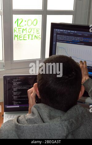 Young man working at home while talking on the phone in a remote meeting. Programmer working from home. Concept of teleworking or telecommuting. Stock Photo