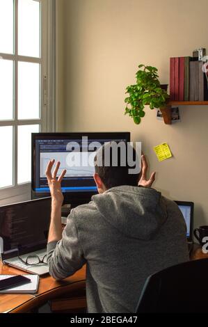 Stressed young man working from home. Small office at home to telework. Concept of telecommuting or teleworking. Stock Photo