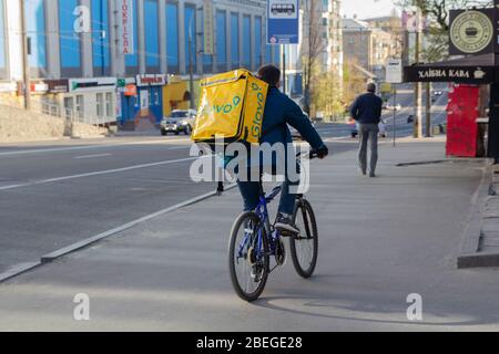 Kiev. Ukraine - April 12, 2020: Delivery service on a bicycle with a backpack in the street during a pandemic Stock Photo