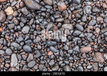 Shiny black stones on along the shore in Hana, Hawaii Stock Photo