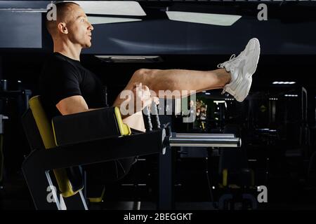 Muscular man pumping press in gym lifting legs Stock Photo - Alamy